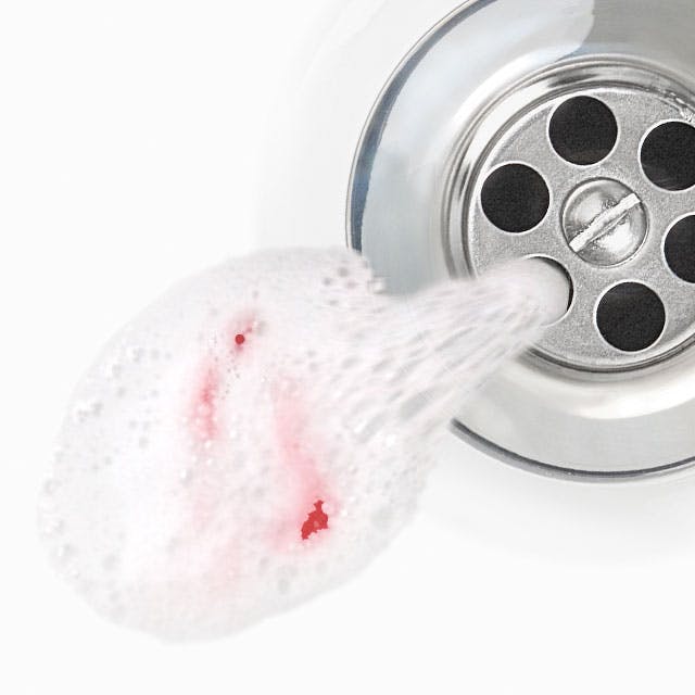 Toothpaste tainted with blood going down a drain.