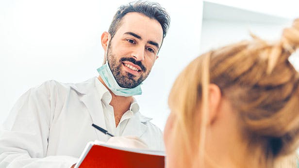 Un dentiste et une patiente lors d'une consultation dentaire pour trouver une solution contre le saignement occasionnel des gencives