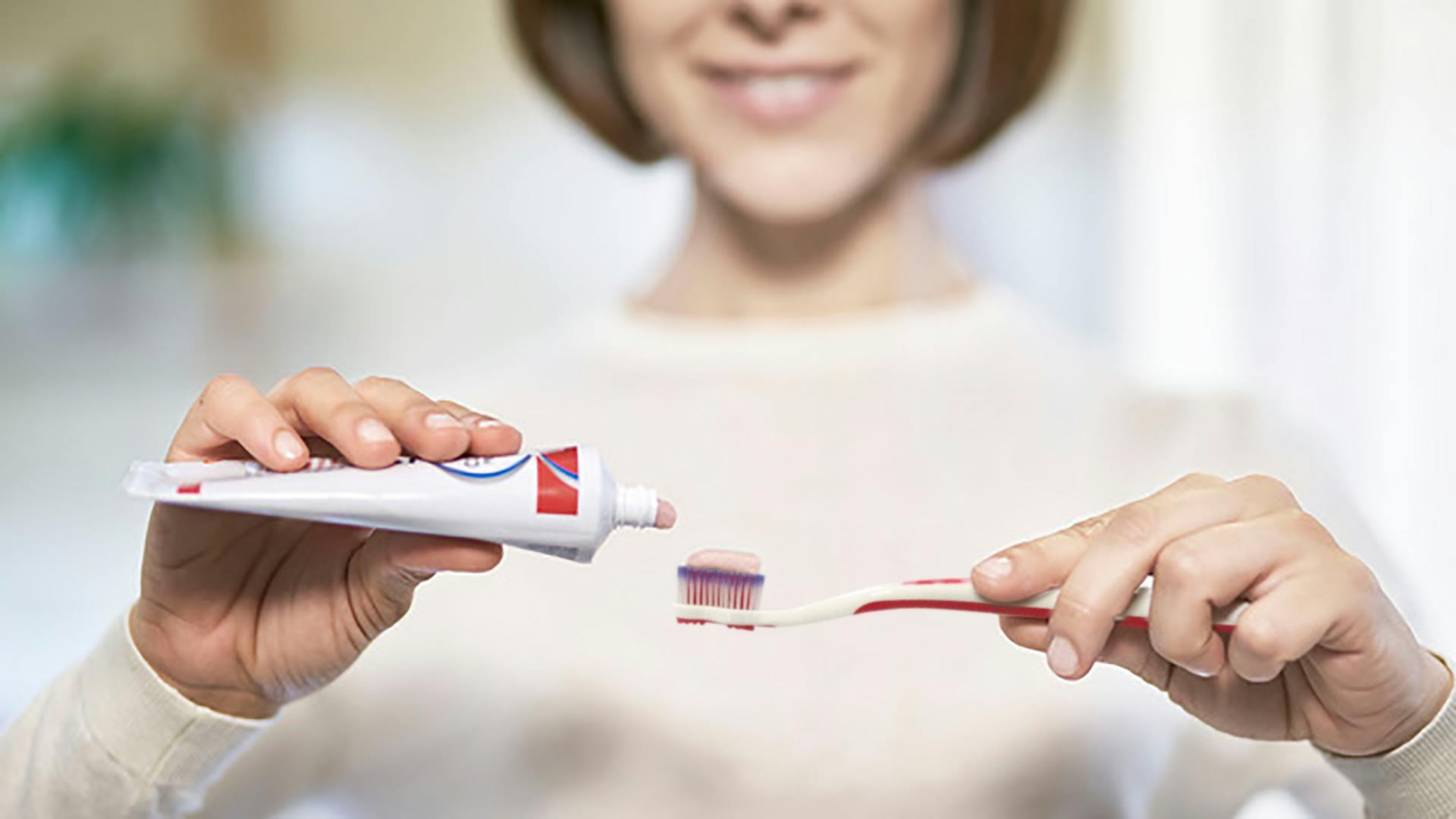 woman putting parodontax Complete Protection toothpaste onto a toothbrush