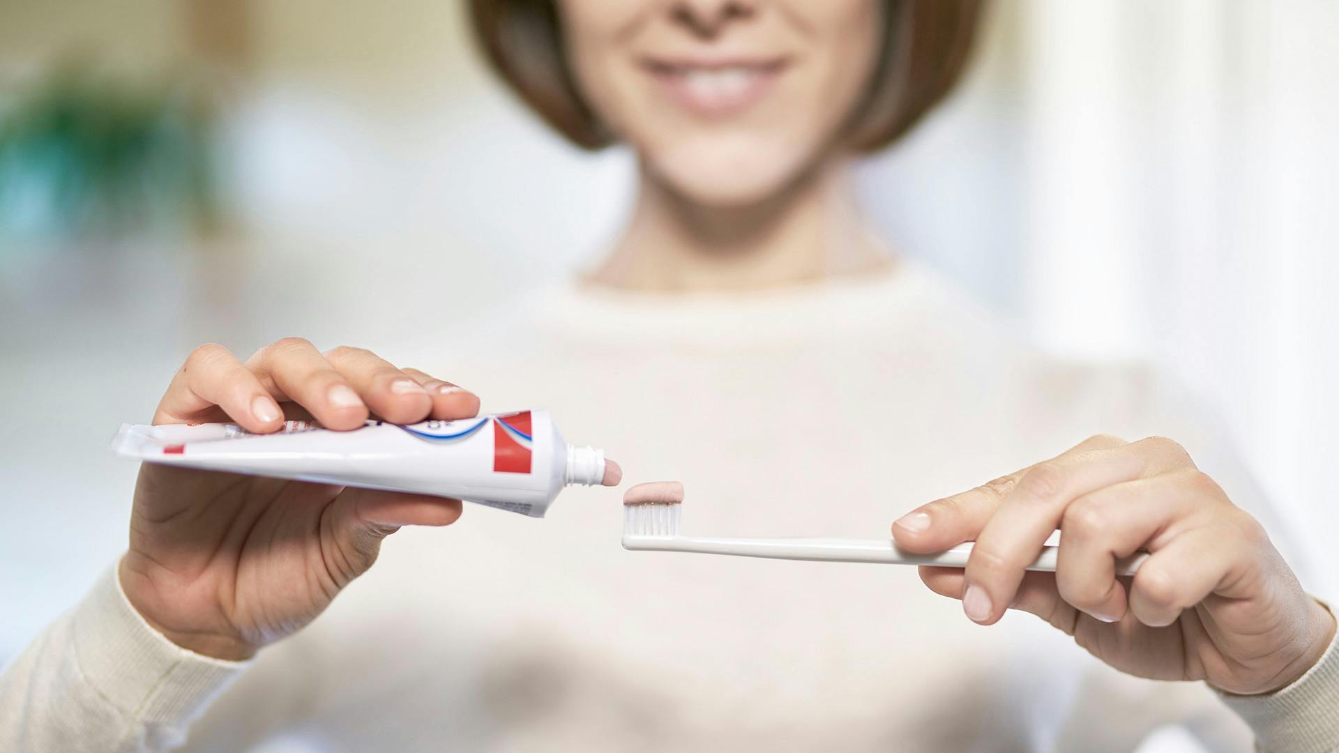 woman putting parodontax Complete Protection toothpaste onto a toothbrush