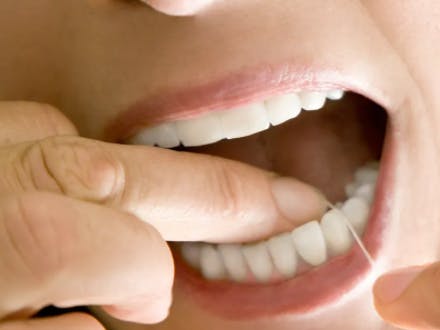 Frau benutzt Zahnseide, um Zahnzwischenräume zu reinigen