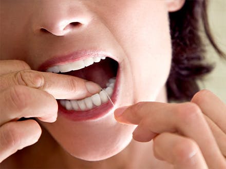 Close-up shot of woman using dental flos