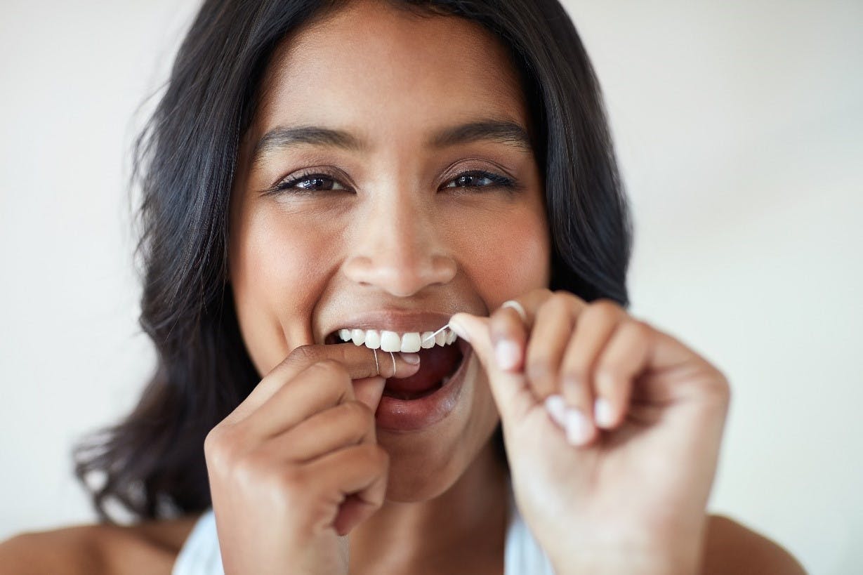 woman looking forward flossing her teeth 