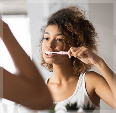 Girl looking in mirror brushing teeth 