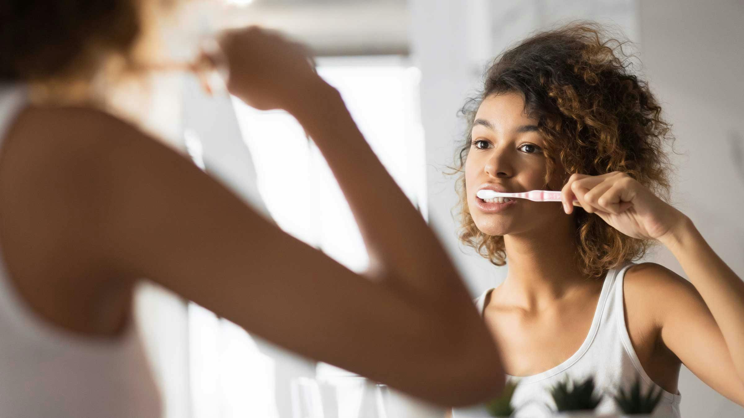 Girl looking in mirror brushing teeth 