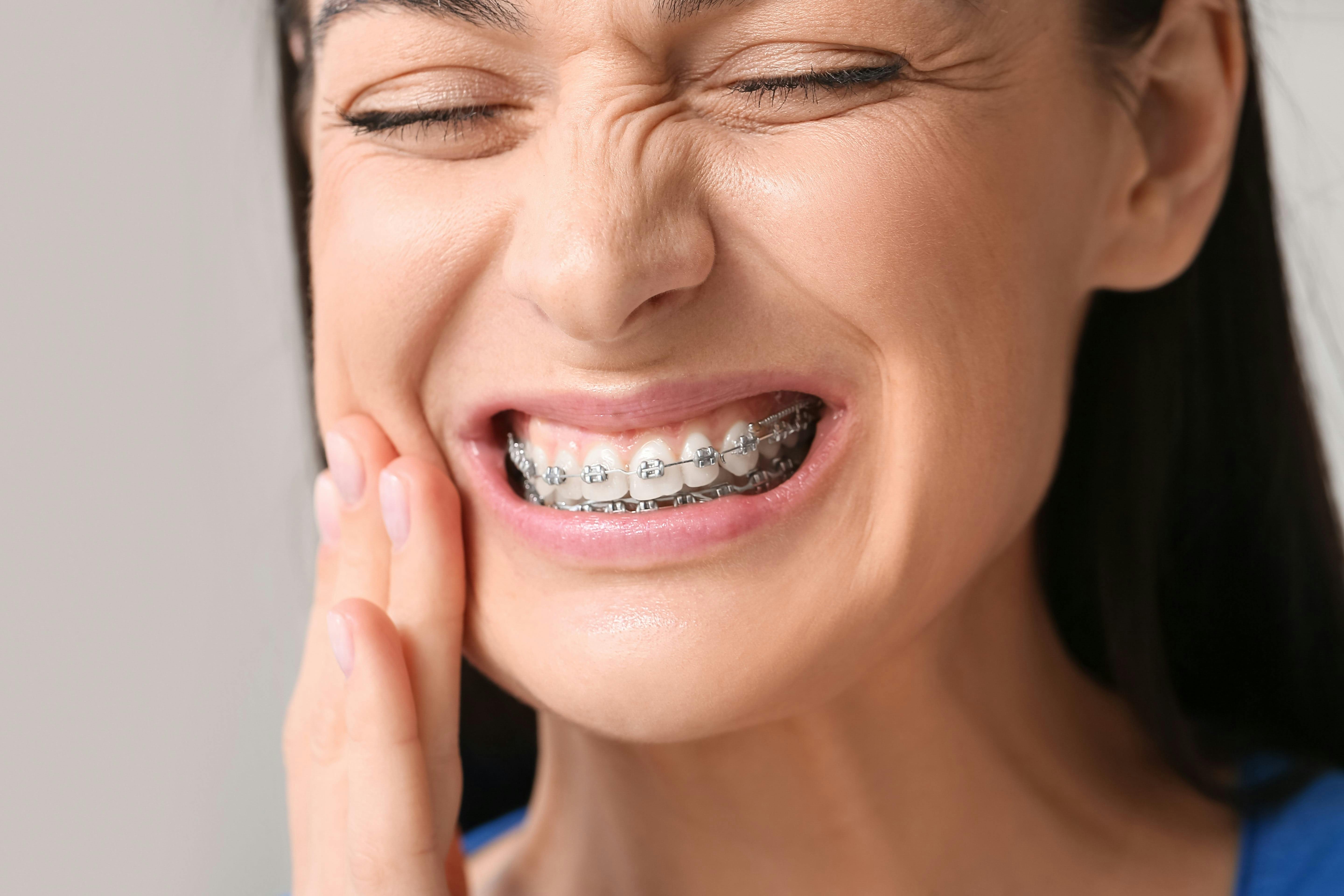 Woman experiencing pain from braces touches her jaw