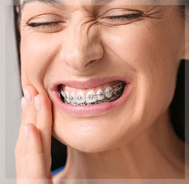 Woman experiencing pain from braces touches her jaw