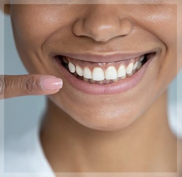 African American woman points to her healthy teeth and gums