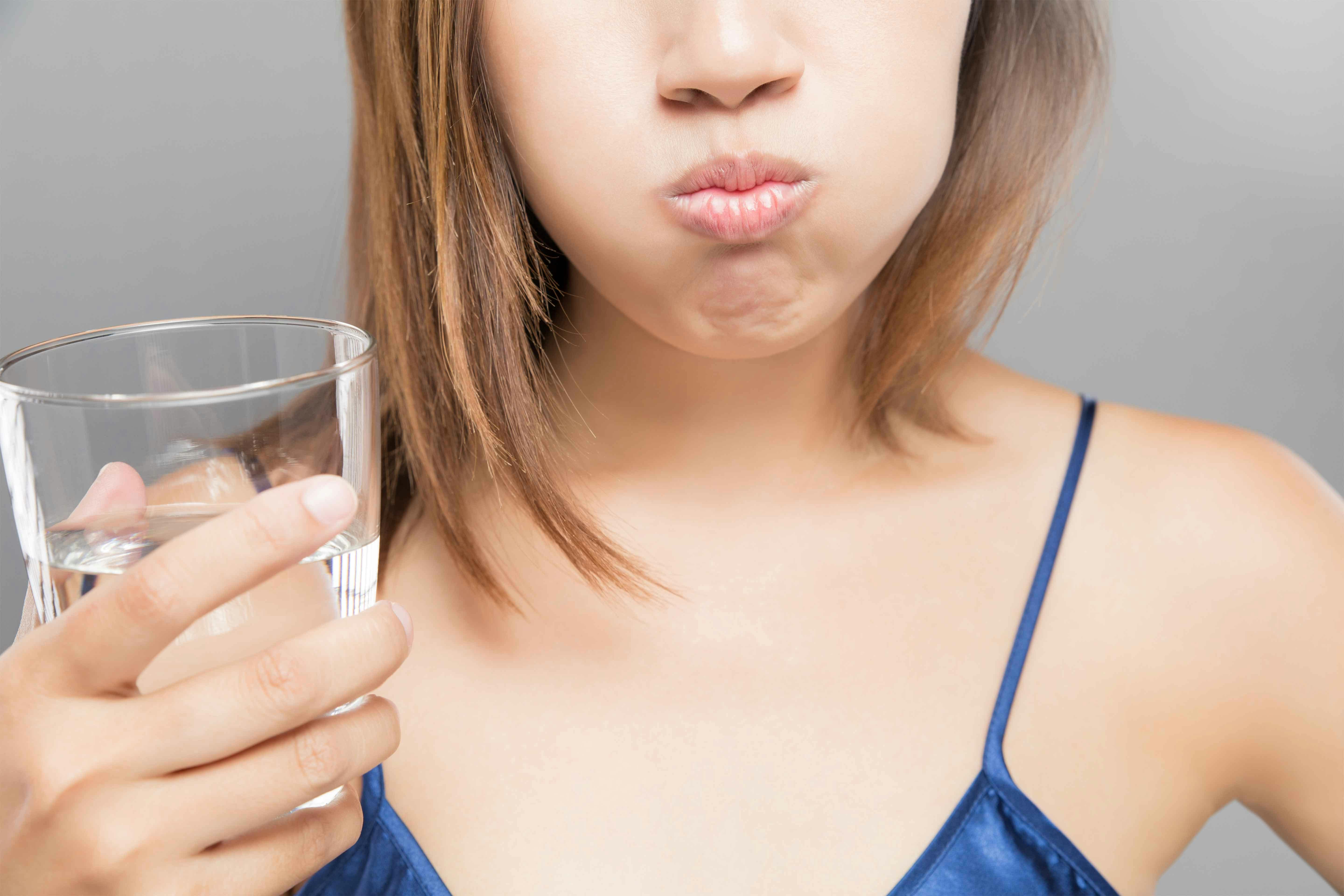 Woman rinsing her mouth with clear mouthwash