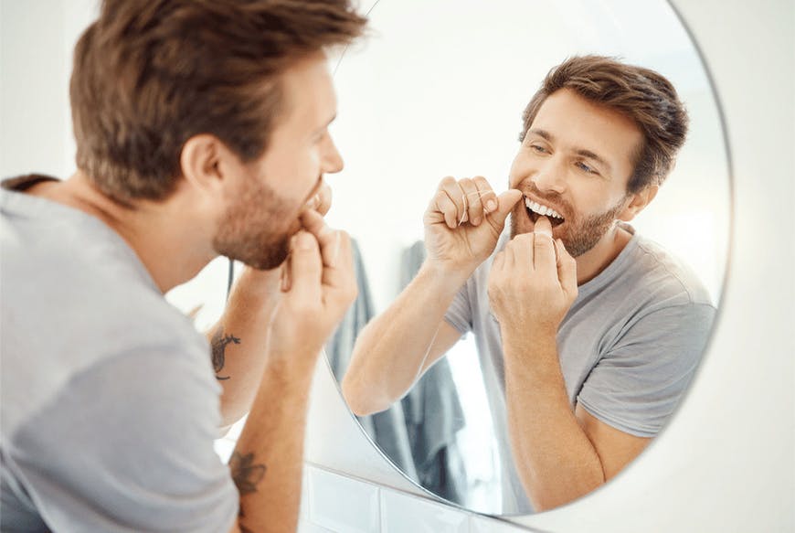 A man flossing in front of a mirror