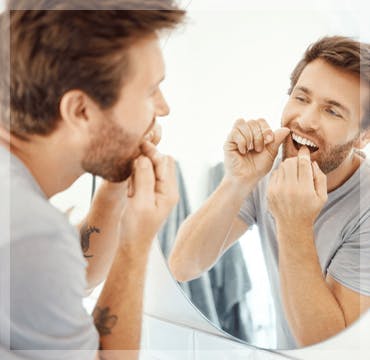 A man flossing in front of a mirror