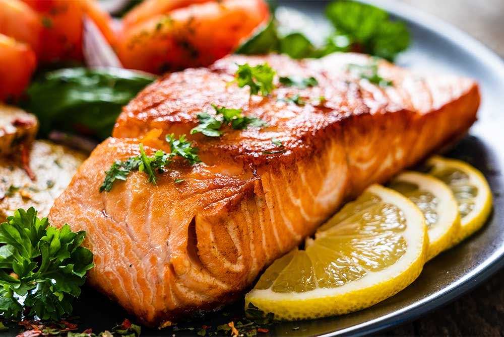 Grilled salmon steak with lemon and herbs on dinner plate