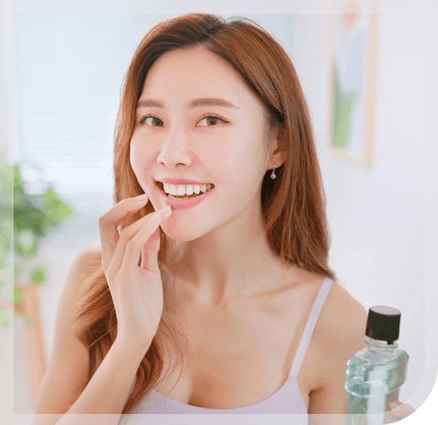 Smiling woman holding bottle of unopened mouthwash with left hand