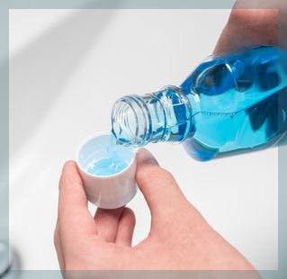 Hands of person pouring mouthwash into cap