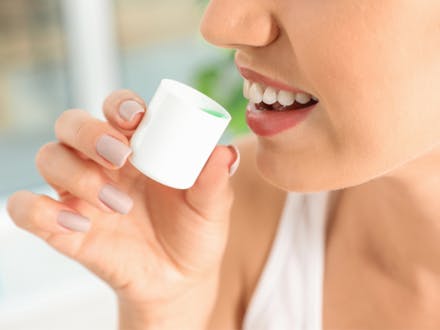 Young woman using mouthwash