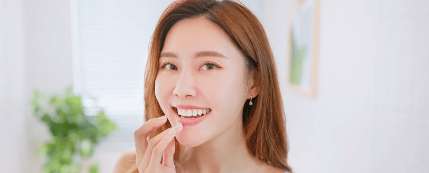 Smiling woman holding bottle of unopened mouthwash with left hand