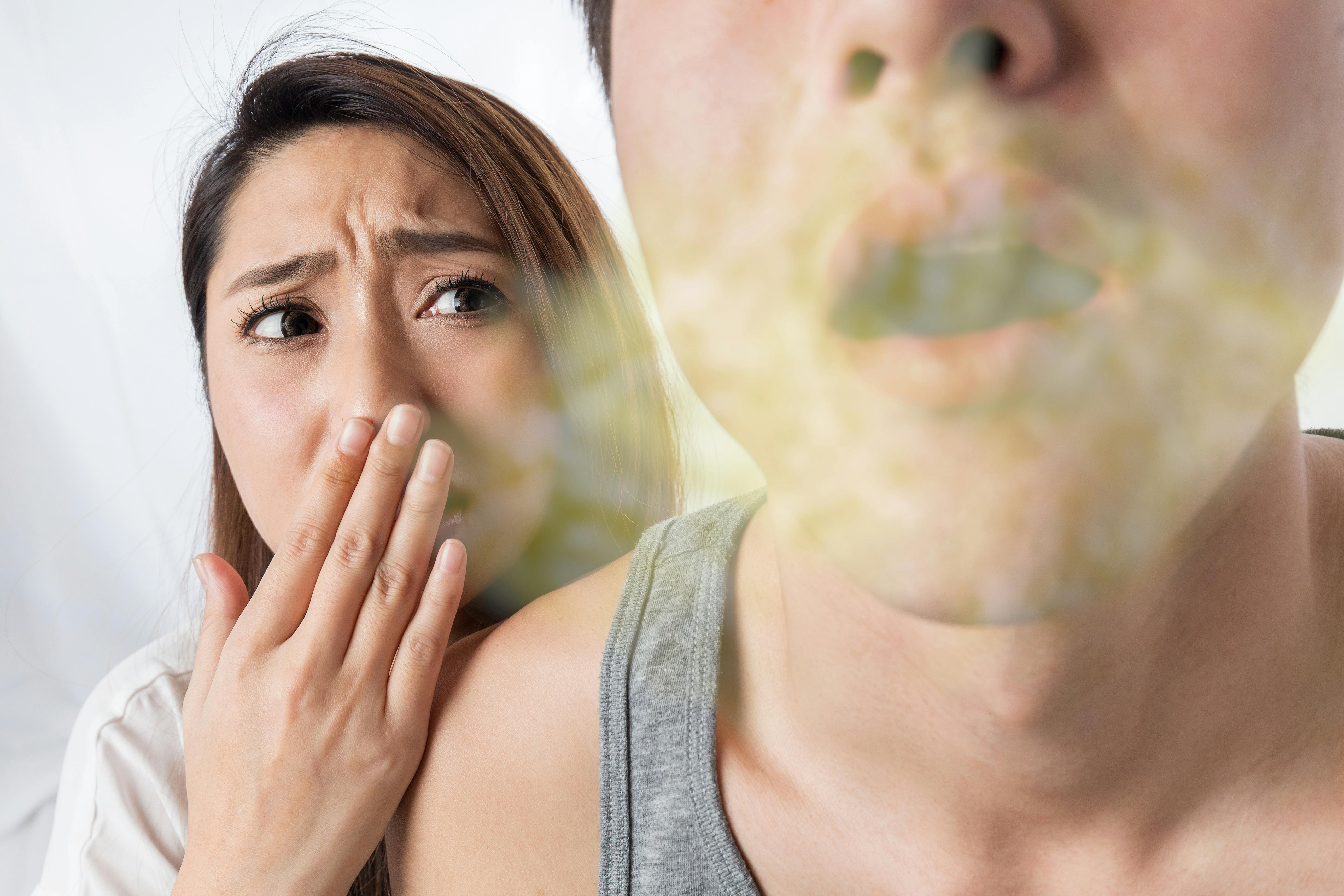 Woman covers her mouth and nose to avoid the bad breath of another person