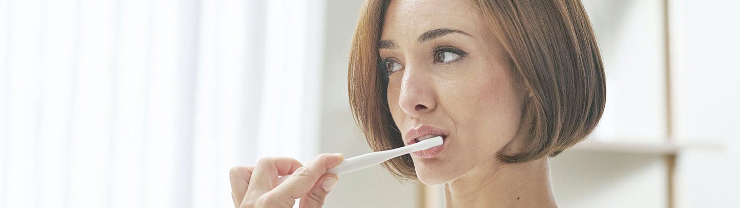 Mulher a escovar os dentes com uma escova parodontax Complete Protection