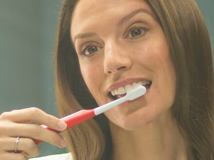 Gift kvinna borstar tänderna varsamt med Parodontax tandkräm