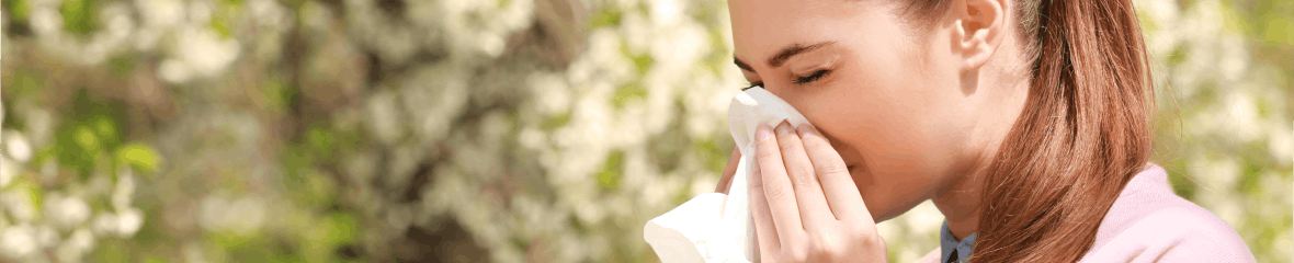 Woman outside close to a tree blowing nose, allergies Woman outside close to a tree blowing nose, allergies
