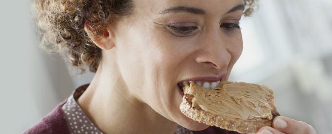 Señora comiendo galleta sin preocupación aún usando prótesis dental - Corega