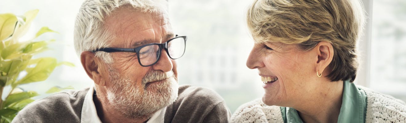 pareja adulta mayor viendose mutuamente y sonriendo gracias a corega