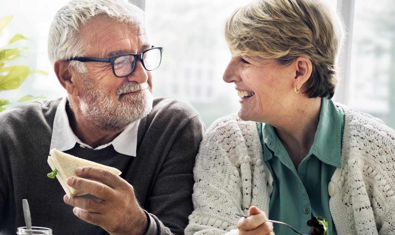 Un couple de personnes âgées discutent en souriant