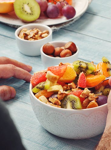 Assiette et petits bols remplis de divers fruits et noix