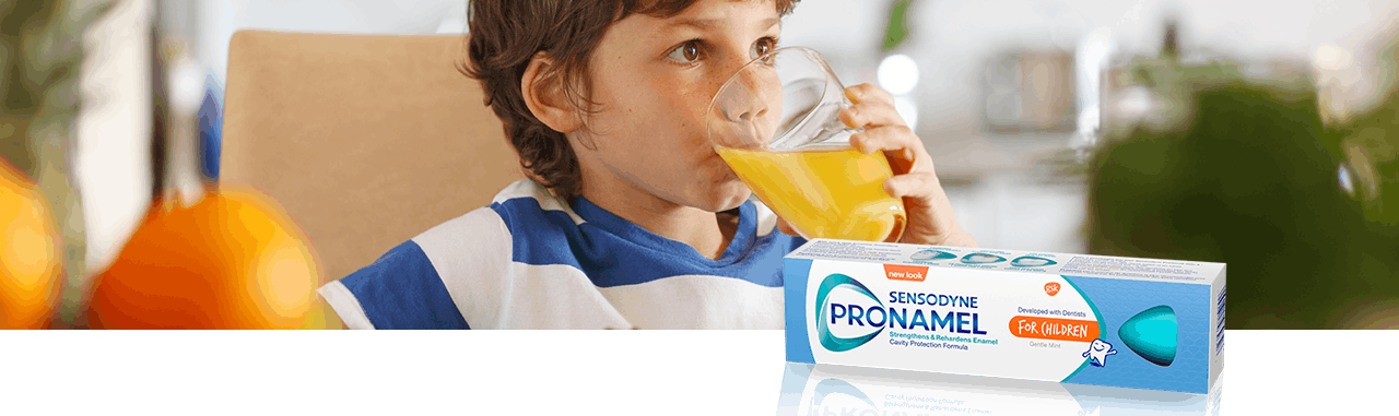 Small boy drinking acidic orange juice from a round glass
