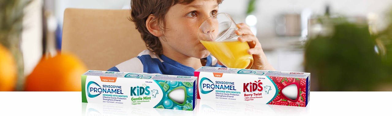 Small boy drinking acidic orange juice from a round glass