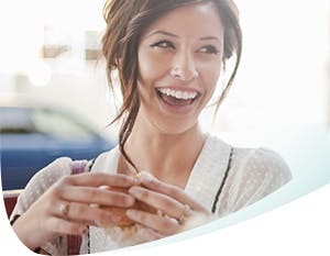 A woman smiling holding a muffin