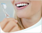 Woman Smiling, Showing White Teeth and Holding a Toothbrush Thumbnail