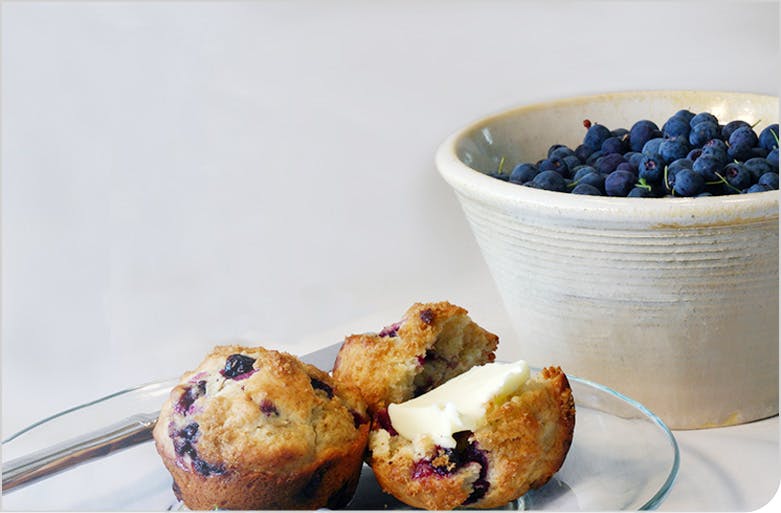 Des muffins aux bleuets à côté d'un bol de bleuets