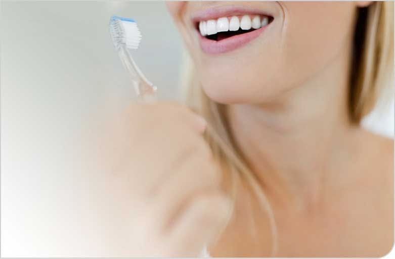 Woman Smiling, Showing White Teeth and Holding a Toothbrush