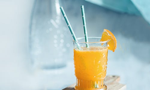 Deux pailles dans un verre de jus d'orange