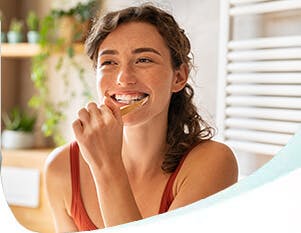 Smiling Young Woman Brushing Teeth In Bathroom