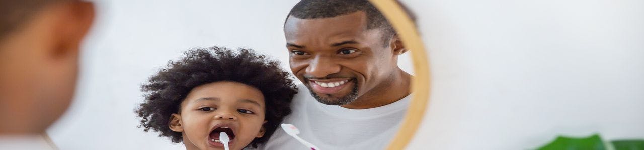 Happy African American Father and Child Brushing Teeth