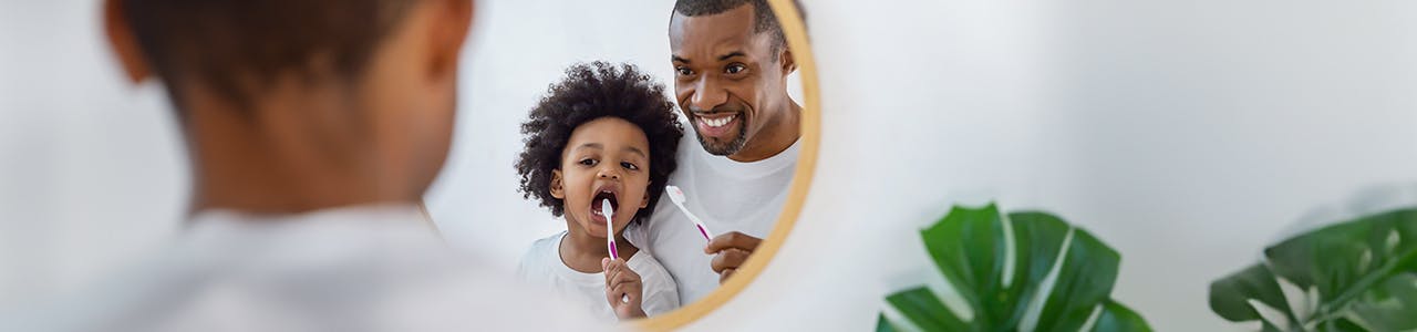 Father and son brushing teeth in front of mirror