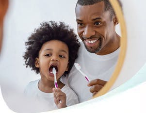 Father and son brushing teeth in front of mirror