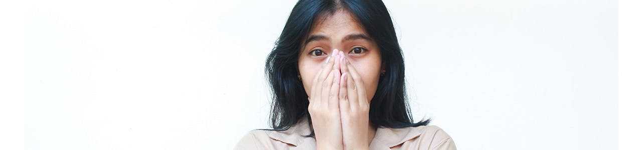 surprised looking woman covers her mouth