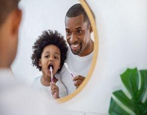 Happy African American Father and Child Brushing Teeth
