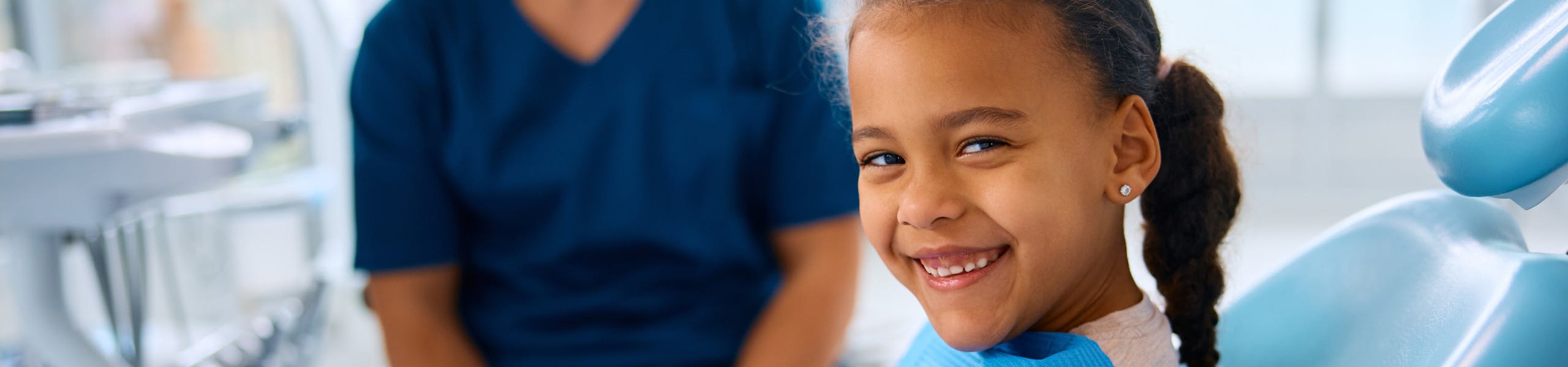 Young black girl sitting in a chair at the dentist’s office and smiling