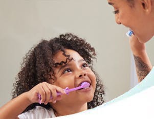 Mother and daughter brushing their teeth together