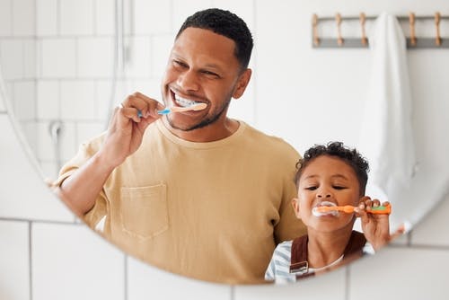 Father and son brushing teeth together