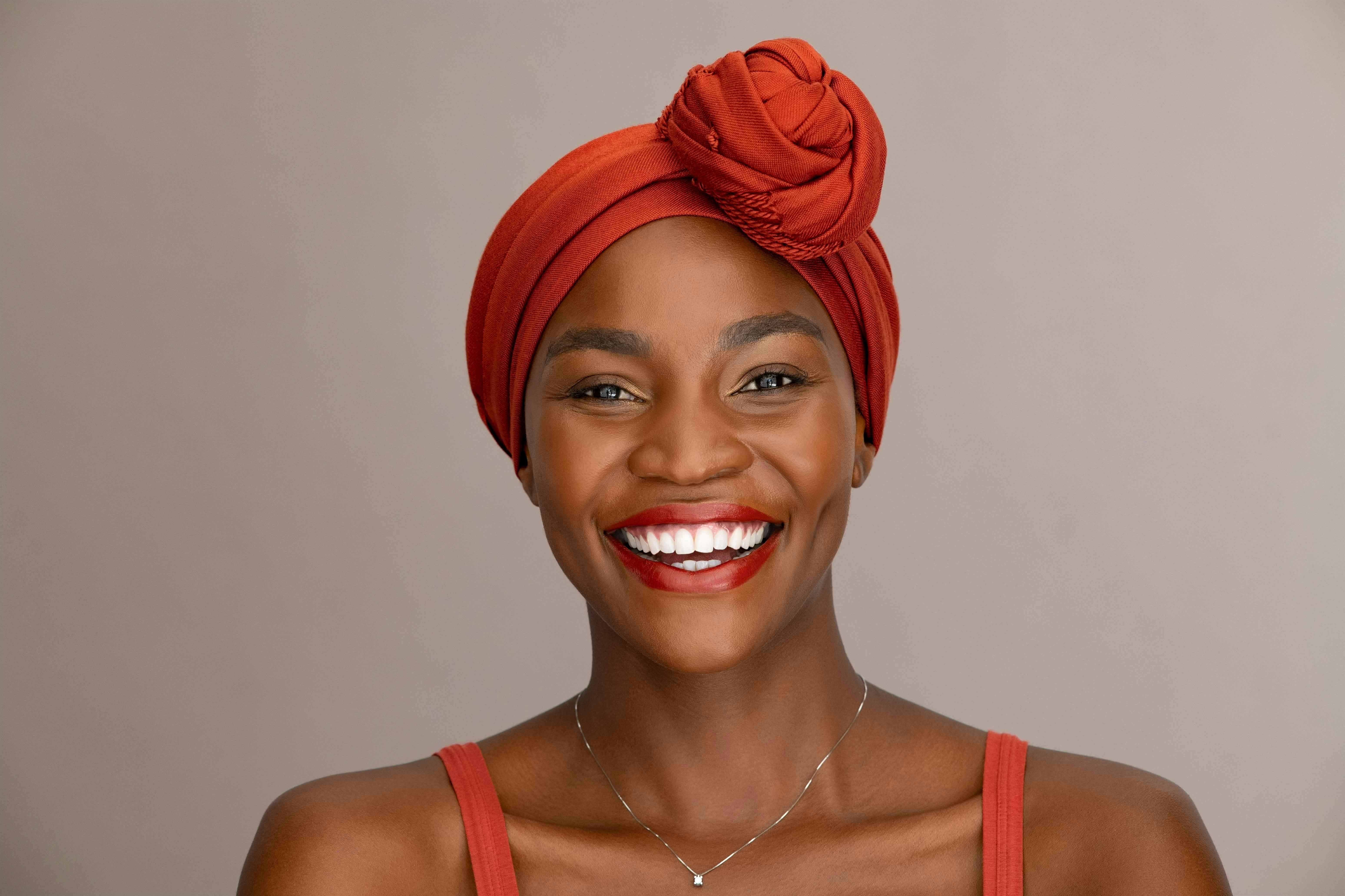 African woman with bright white teeth and red headscarf