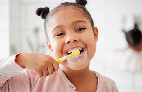 Child smiling and brushing teeth