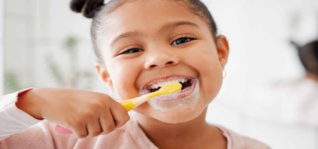 Child smiling and brushing teeth