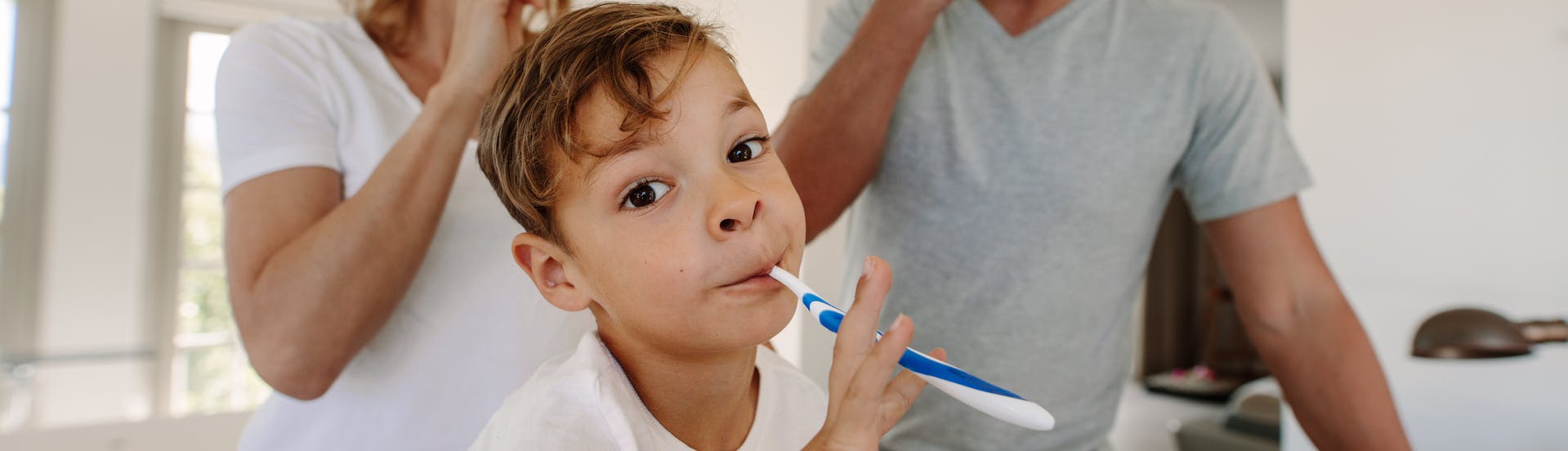 A child and their parents brushing their teeth together