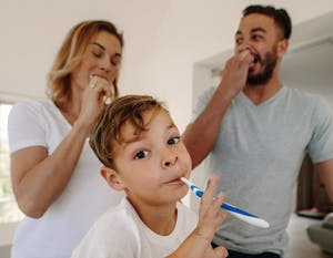 A child and their parents brushing their teeth together