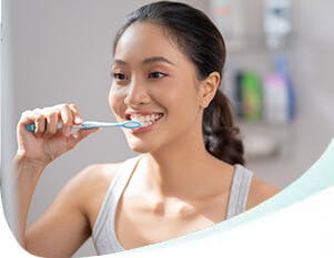 Woman brushing her teeth with a blue and white toothbrush